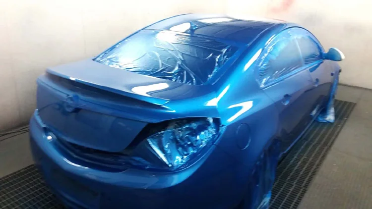 El mismo coche azul metalizado en la cabina, visto por detrás