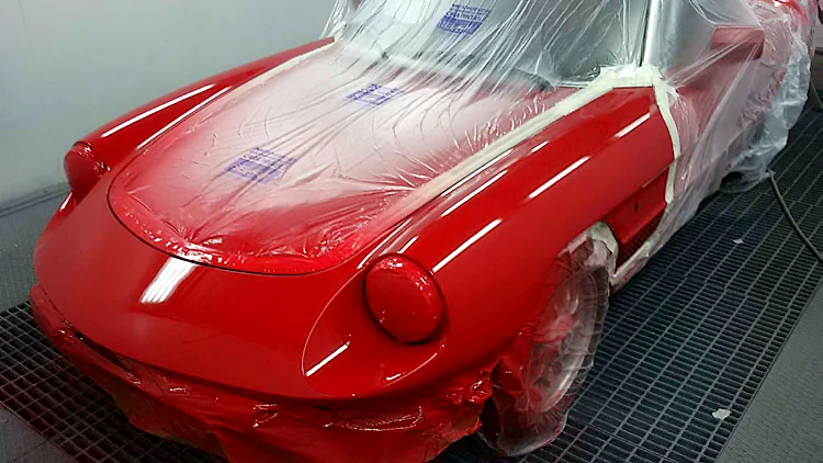 Descapotable clásico rojo recién pintado y enmascarado en la cabina
