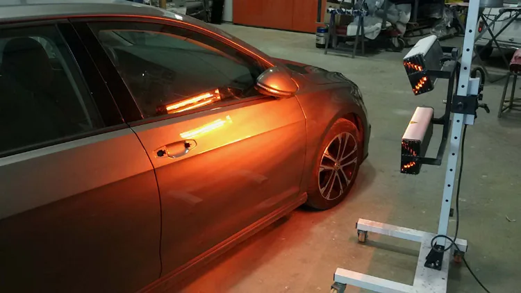 Coche gris bajo las lámparas de secado por infrarrojos tras pintar